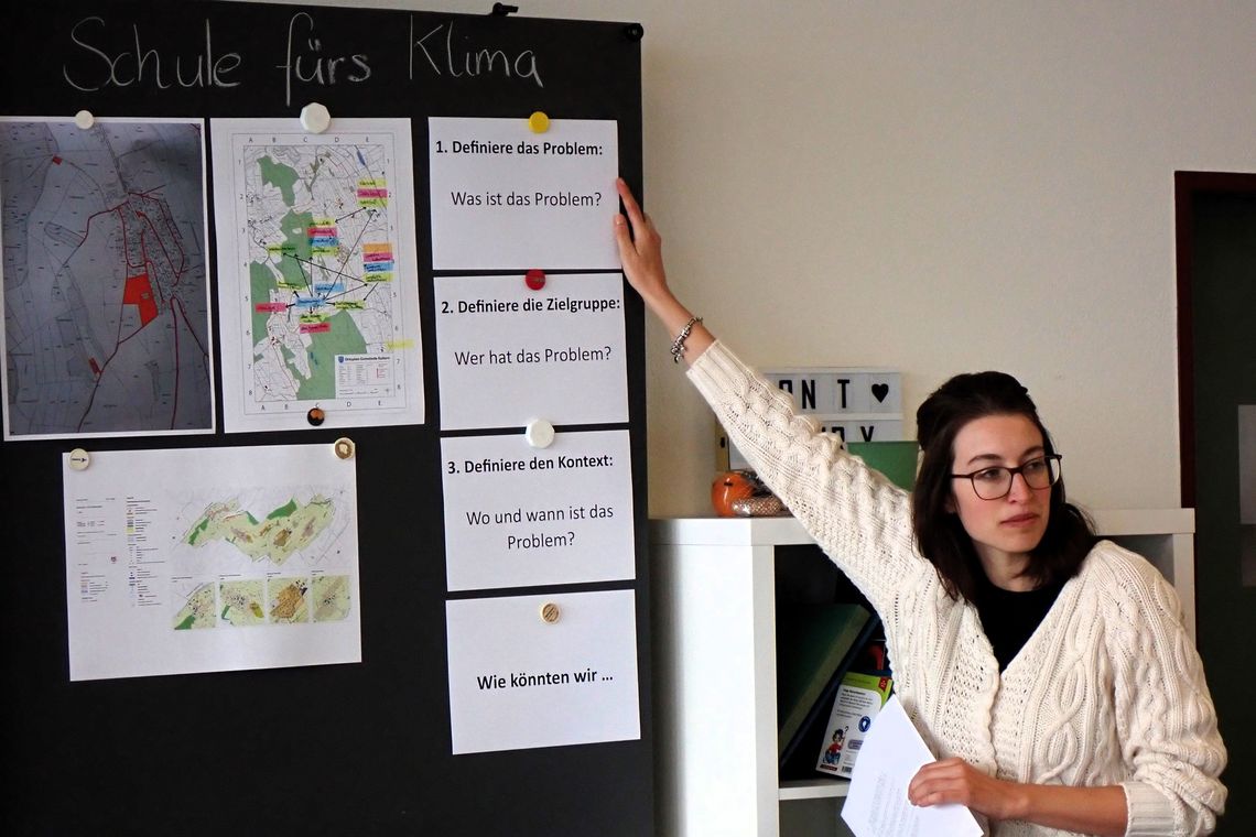 Lehrerin erklärt an Wandtafel Klimaprojekt