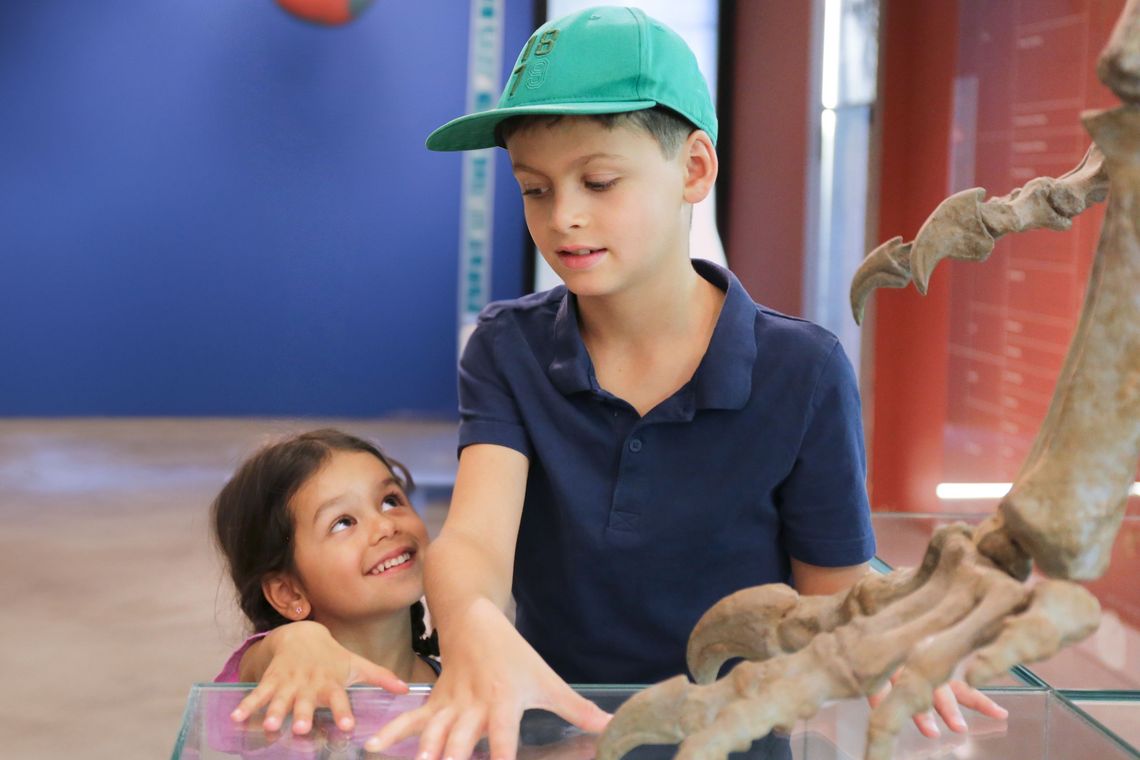 Kinder halten ihre Hände heben Dinosaurierfuss