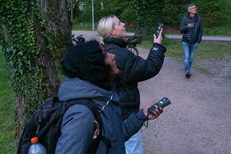 Zwei Frauen und ein Mann draussen in der Abenddämmerung auf Fledermaus-Exkursion.